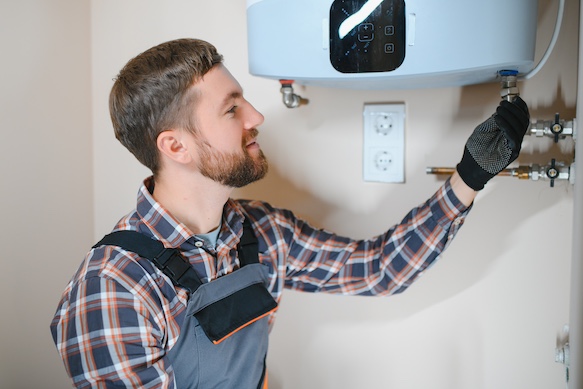 serwisant pieca gazowego z Rzeszowskiej naprawy pieca odkręca śrubę w piecu gazowym